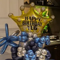 A close-up of the personalized "Happy Birthday YUG" crown foil balloon, the highlight of this unique arrangement.