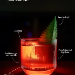 The Red Banana cocktail, a stunning creation with red banana vermouth, Campari, mezcal, and sandalwood tincture, garnished with a beetle leaf. A true sensory experience.