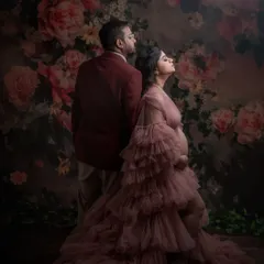 An artistic and dramatic pose with the couple standing back-to-back. The lighting highlights their profiles and the texture of the gown, creating a fine art portrait with a high-fashion feel.