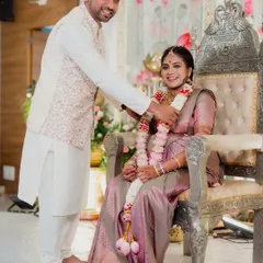 Capturing a key ritual during a Seemantham, or traditional baby shower. The ornate silver throne and floral backdrop highlight the importance and beauty of the ceremony.