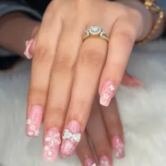 Nail art for the win! This highly embellished set features a pink glitter base with 3D flowers, sparkling rhinestone bows, and delicate pearl accents for a truly glamorous look.
