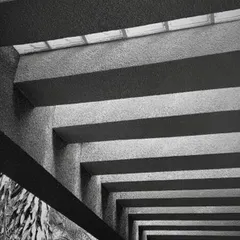 The play of light and shadow brings my designs to life. Here, the strong lines of concrete beams create a powerful rhythm, while a skylight filters soft light from above, demonstrating how texture and light can define an atmosphere.