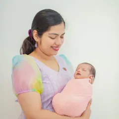A mother smiling as she cradles her baby. These portraits are designed to feel natural and relaxed, providing a comfortable experience for Bangalore families.