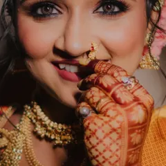 A bride's joy is radiant. This close-up portrait captures the intricate details of her henna, the sparkle in her eyes, and the traditional nath that is so central to Maharashtrian bridal beauty.