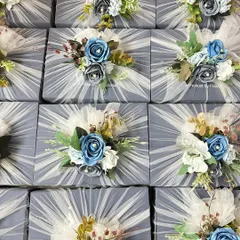 A large order of corporate gift hampers ready for delivery. Each box is elegantly wrapped in grey and white tulle, topped with a custom blue floral arrangement, creating a consistent and professional look.