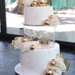 I love adding a little bit of drama with fairy lights! This three-tier white and gold wedding cake has a clear separator tier filled with twinkling lights, decorated with white peonies and gold accents for a magical touch.