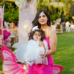 A beautiful mother and daughter portrait from a butterfly themed birthday party. The birthday girl looks adorable in her white dress, posing with her mom in front of the themed decor.