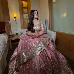 A full-length shot of the Roka outfit. The soft glam makeup perfectly complements the elegant pink and gold lehenga.