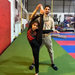 I work directly with my gymnasts to safely push their limits. Here, I'm assisting a student with her standing split, helping her achieve maximum flexibility while maintaining proper alignment.