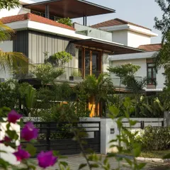 Viewed through the surrounding foliage, the villa's new architectural layers are revealed. The timber and steel pergolas add a lightweight, modern counterpoint to the original structure, integrating it with the lush garden.