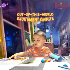 Out-of-this-world excitement awaits! A young boy is deep in concentration while working on his space-themed craft. Our workshops are designed to fuel curiosity and creativity.
