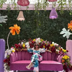 Taking a moment to relax on a vibrant pink sofa at a carnival-themed event. This lifestyle shot is perfect for showcasing event decor and fashion.