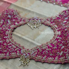 The back of a rani pink bridal blouse, featuring a heart-shaped cutout lavishly framed with intricate zardosi, stone work, and pearl tassels.