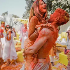 Pure, unadulterated fun. This shot captures the wild and colorful aftermath of a Haldi, with the groom lifting his laughing bride, both covered in turmeric and color.
