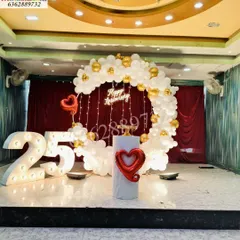 A stunning Silver Jubilee celebration for a 25th anniversary, with a white and gold balloon ring, fairy lights, and a large illuminated number '25'.