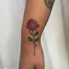 A classic and timeless red rose tattoo on the forearm. The vibrant color and clean line work make this a beautiful and elegant piece, symbolizing love and passion.