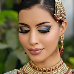 Eyes closed to reveal the subtle blend of eyeshadow with a pop of blue, complementing the bold liner.