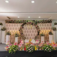 A beautiful stage we designed for a baby shower, featuring a circular floral arch as the centrepiece. The setup is complemented by a traditional patterned backdrop, elegant white pedestals with flower arrangements, and soft candle lighting.
