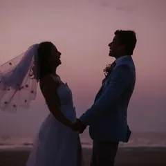 A silhouette filled with laughter. This candid shot captures the pure joy and happiness of the newly married couple on the beach at dusk.