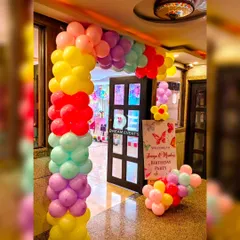 A vibrant rainbow balloon arch creates a fun and exciting entrance for a butterfly-themed twin birthday party.
