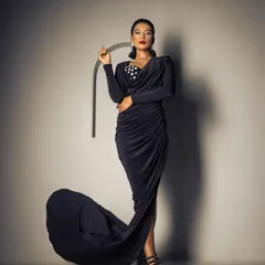 A dramatic, full-length shot for a fashion brand. The look features a sleek, pulled-back hairstyle and bold red lips, creating a powerful and elegant silhouette.