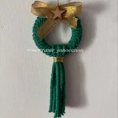Decorate your Christmas tree with this handmade macrame wreath ornament. The green wreath with a gold bow and tassel adds a touch of rustic, festive charm.