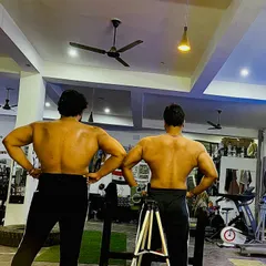 Hitting a back double bicep pose with my training partner after a heavy deadlift session.
