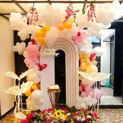 A dreamy birthday setup with balloon clouds, hanging floral arrangements, and illuminated leaf props. This unique design uses a modern arched backdrop and a neon 'Happy Birthday' sign to create a whimsical, picture-perfect celebration space.
