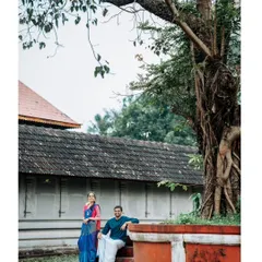 The couple relaxing under a large banyan tree, a classic element in South Indian landscapes. This shot captures a peaceful, candid moment away from the main temple structure.