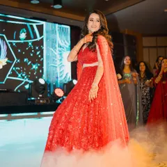 The perfect shot of a bride owning the stage. The combination of a stunning red lehenga, dramatic smoke, and confident moves makes for an unforgettable solo.