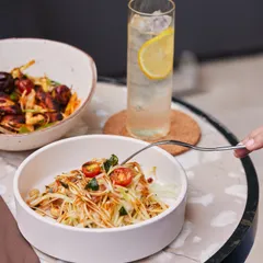 Our vibrant raw papaya salad is a fresh and wholesome option for a light lunch. It's paired here with a glass of our house-made ginger ale for a refreshing and balanced meal.