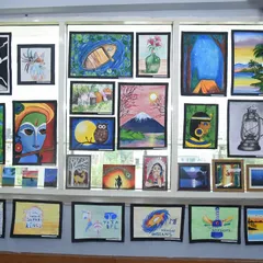 A beautifully curated window display of student paintings. We use every corner of our space to celebrate art, showing a mix of styles including portraits, still life, and abstract pieces created in our drawing and painting courses.