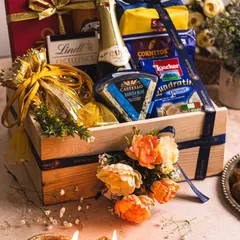 The 'UTSAV' hamper, designed for luxurious wedding and in-room favours. This professionally shot image captures the premium selection of snacks, chocolates, and wine against a festive backdrop with diyas, highlighting its celebratory feel.