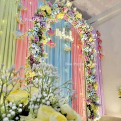 A detailed shot of the pastel Mehendi decor, focusing on the floral arrangements and the gentle glow of the fairy lights.