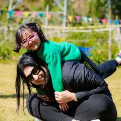 A mother and daughter share a playful moment on the grass. Our open green spaces are perfect for families to relax, play, and just be together.