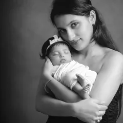 A tender black and white portrait of a mother holding her sleeping newborn. The simplicity of monochrome emphasizes the peacefulness and love in this moment.