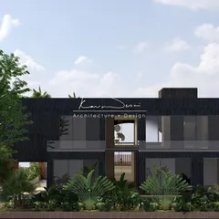 A modern, two-story home designed with a bold, dark facade. The large glass windows and open balconies prevent the structure from feeling heavy, while the surrounding tropical plants ground it in its environment.