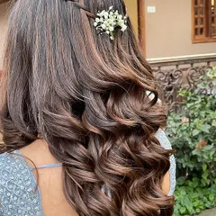 A pretty and simple open hairstyle for a bridesmaid or guest. The soft curls are given a touch of elegance with a simple braid and fresh flowers.