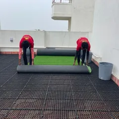 Our team rolling out the high-quality artificial turf over the drainage mats. We ensure the installation is done professionally for a seamless and long-lasting lawn.