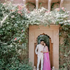 A fairytale moment for Saloni and Kanav, framed by a traditional Rajasthani doorway and beautiful bougainvillea. This shot blends natural beauty with stunning heritage architecture.