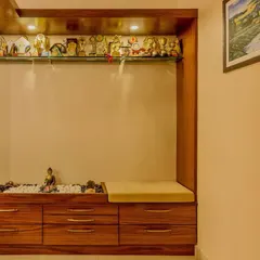 A functional foyer designed to be a pause point before entering the main home. This custom wooden unit combines a shoe cabinet, a comfortable seating bench, and an illuminated shelf for displaying personal treasures.