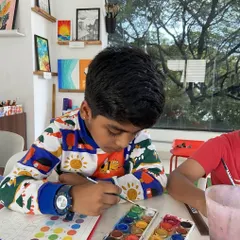 A young student in our kids' class is focused on his watercolor painting. We introduce children to a variety of mediums, like this watercolor set, to help them discover different techniques and find what they enjoy most.