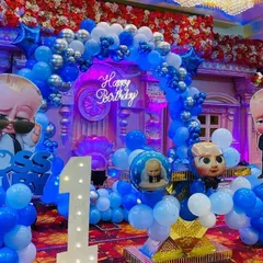 A close-up of the 'Boss Baby' birthday theme, showing the character cutouts, balloon columns, and a 'Happy Birthday' neon sign against a grand backdrop.