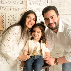A heartwarming family photo. Parents smile warmly with their happy toddler, showcasing the love and joy of their family.