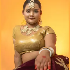 A seated portrait showcasing the full styling of our vintage theme, from the golden blouse to the intricate jewelry. The warm, solid background keeps the focus entirely on the model.