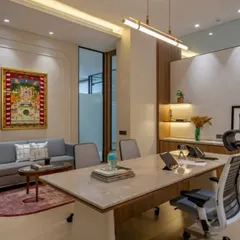 A luxurious executive cabin featuring a marble-topped desk, elegant wall molding, and a comfortable seating area. The space is personalized with traditional Indian artwork, reflecting the client's taste.