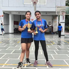 Two of our standout players from the junior girls' team proudly displaying their winner's trophy and MVP award. Their performance is a direct result of the discipline and advanced skills we cultivate at the academy.