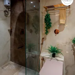 A view of the shower area, separated by a glass partition. The dark accent tile in the shower adds depth and contrast to the space.