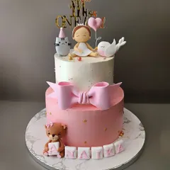 A cake that is just "Ati Sundar". This two-tier cake for Naika's first birthday is pure elegance, with a big pink bow, a teddy bear, and a cute figurine with her animal friends.