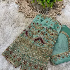 This pastel green blouse features exquisite embroidery with peacock motifs, highlighted with maroon and gold thread. It's a piece of wearable art.